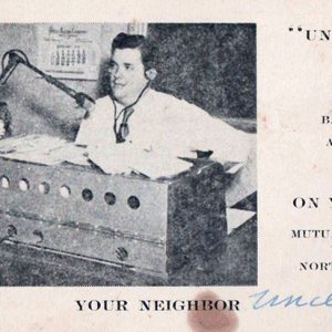 White man sitting in radio station with text on post card