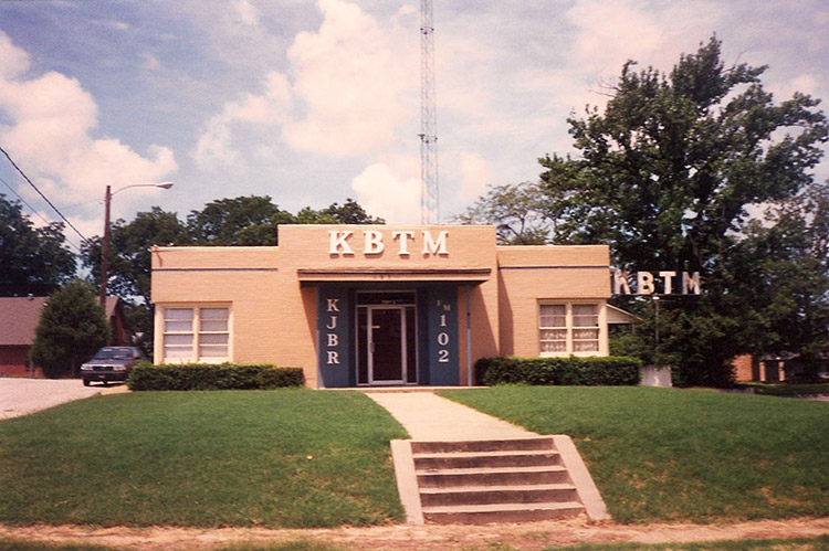 Single-story K.B.T.M. building with tower in the background