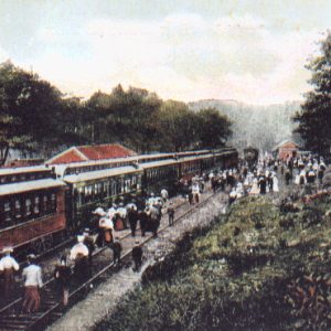 Passenger train on tracks at station with passengers beside it