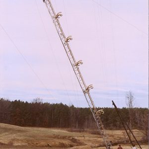 Workers raising a radio tower in a field