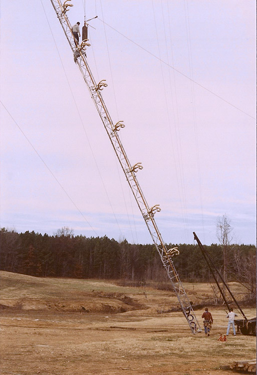 Workers raising a radio tower in a field