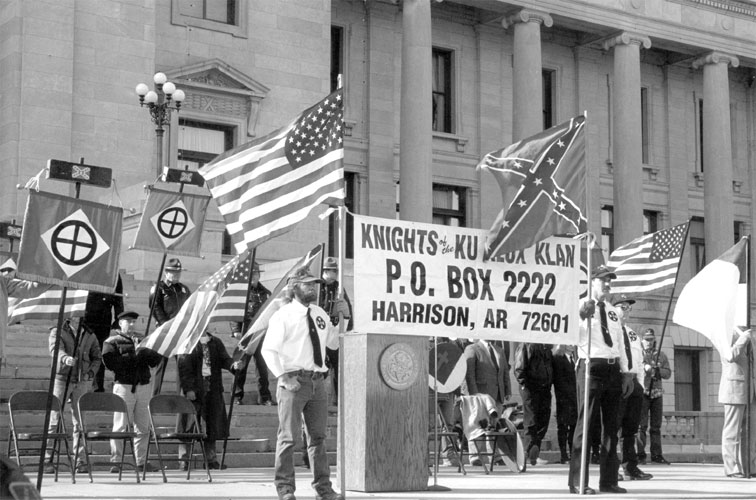 White men with flags and "Knights of the Ku Klux Klan" sign from Harrison speaking at the State Capitol