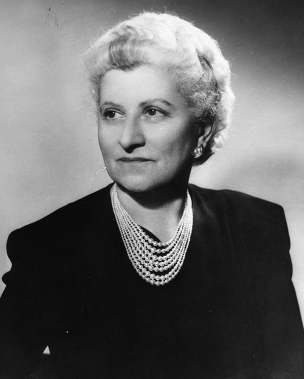 Older white woman in black with pearl necklaces