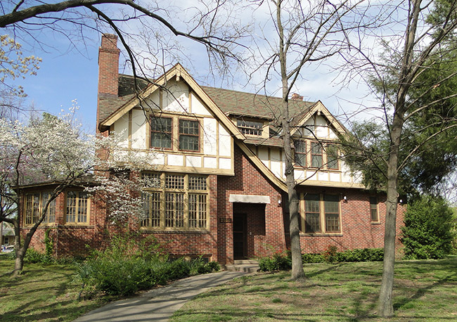 Two-story wood and brick house with trees and walking path