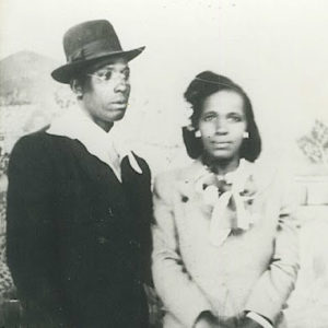 Young African-American man in fedora hat and suit standing with young African-American woman