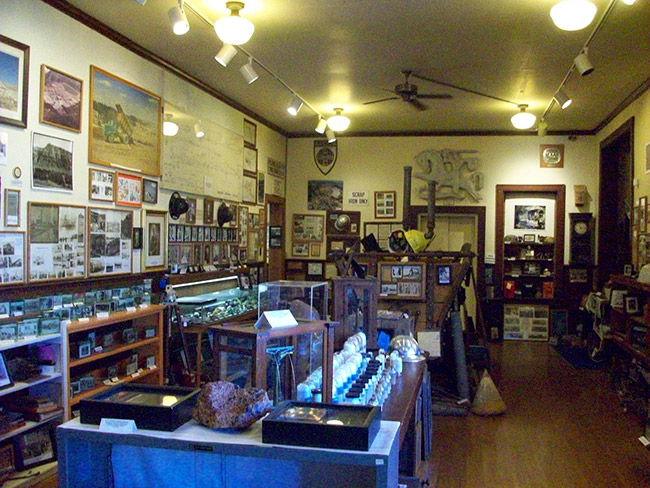 Mine cart framed photographs and equipment on display in room with hardwood floors