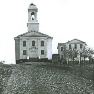Two-story church building with bell tower attached to two-story school house