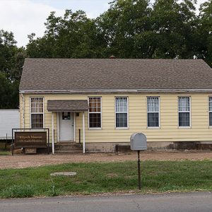 Single-story building with yellow siding and semi trailer behind it
