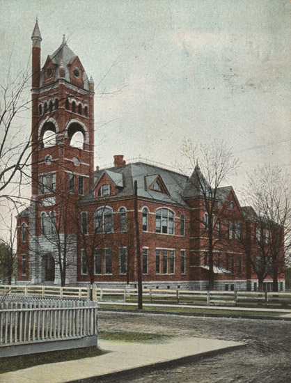 Three-story brick building with tall bell tower and spire