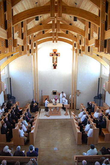 Interior of church building with curved wood ceiling with congregation during service