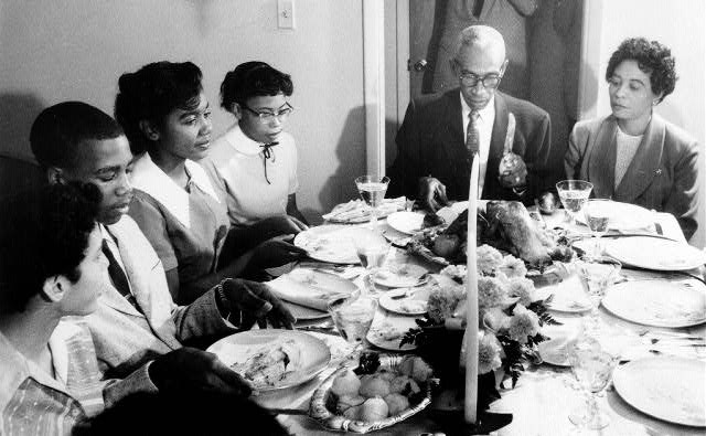 Older African American man and woman at dinner table with younger African American boys and girls