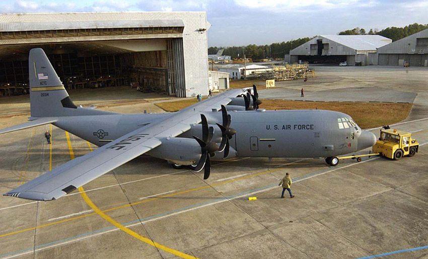Propeller-driven transport plane being towed from hanger