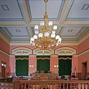 Interior court room with large gilded chandelier wooden furniture leather chairs ornate moulding
