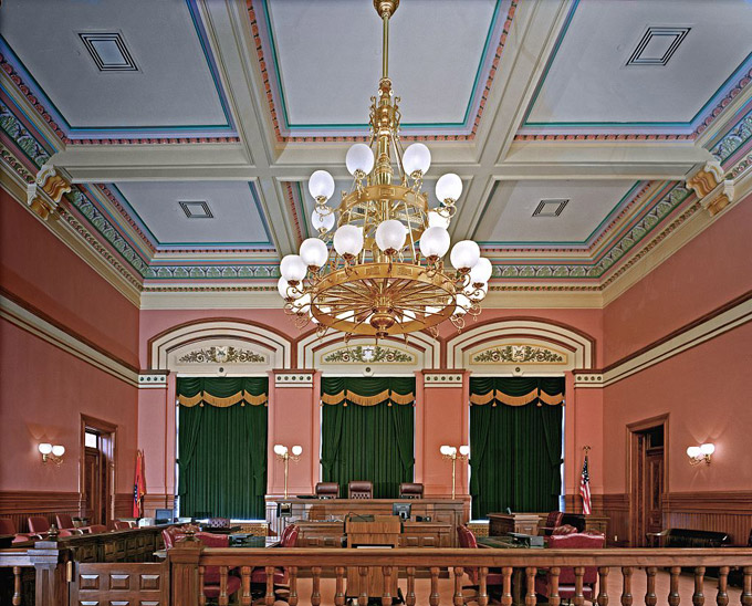 Interior court room with large gilded chandelier wooden furniture leather chairs ornate moulding