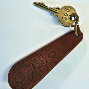 Brass key with the number 906 engraved on it and leather key fob