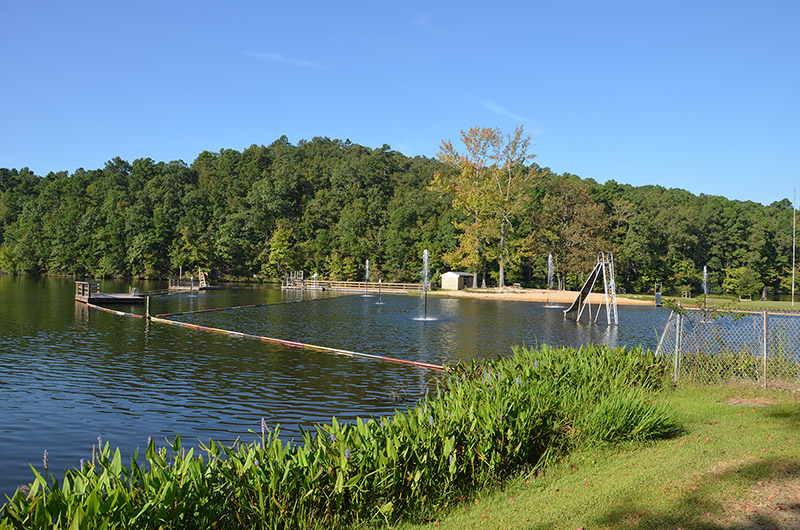 roped off swimming area with slide on lake with trees in the background