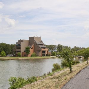 Lake with trail and modern multistory brick building and trees
