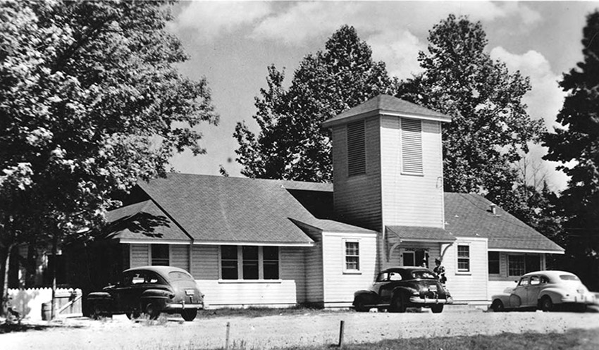 Cars parked outside building with tower and covered entrance