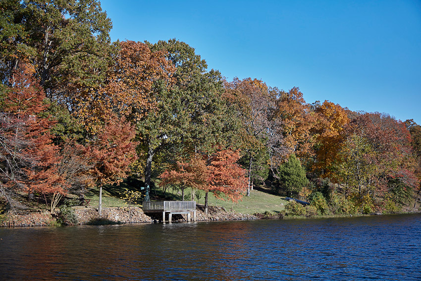 Looking across lake with dock on shore under autumn trees