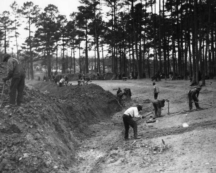 Group of African-American men digging in field with mounds of dirt behind them