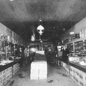 Group of men inside store with merchandize in display cabinets and on walls