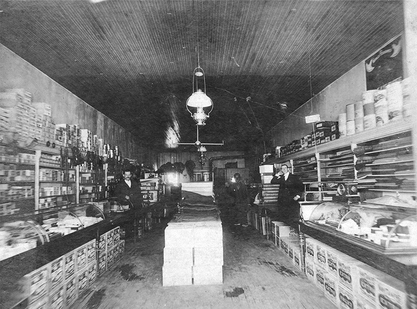 Group of men inside store with merchandize in display cabinets and on walls