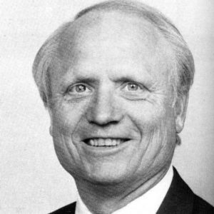 Older white man smiling in suit and tie