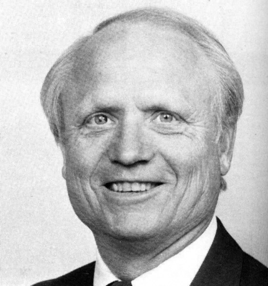 Older white man smiling in suit and tie