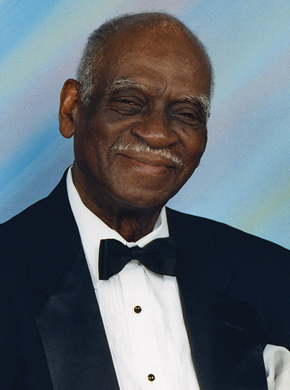 Older African-American man with mustache smiling in suit and tie