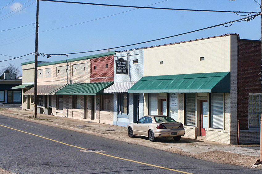 Brick storefronts with parked car on street and power lines