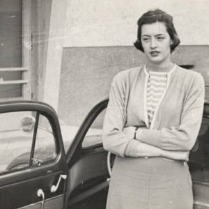 White woman standing with arms crossed and car door open