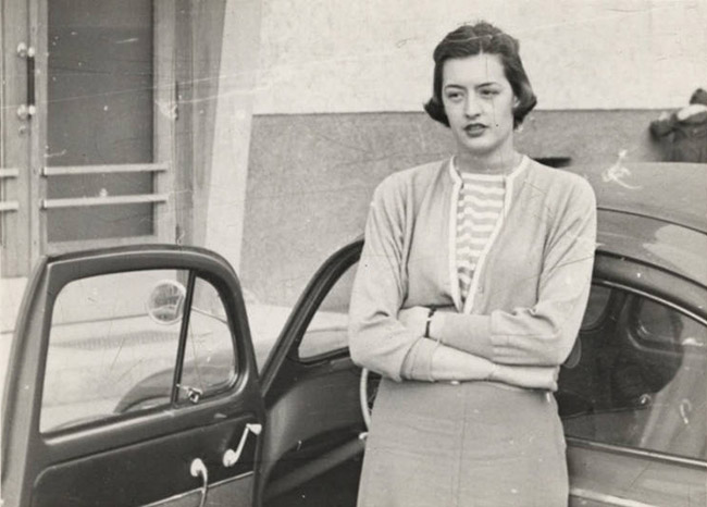 White woman standing with arms crossed and car door open