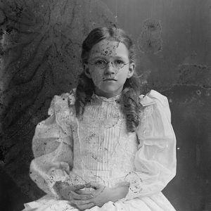 Young white girl with glasses sitting in dress