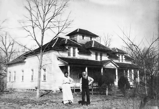 white man and woman standing outside multistory house with covered porch