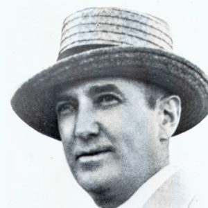 White man with straw hat in suit and tie wearing a carnation corsage
