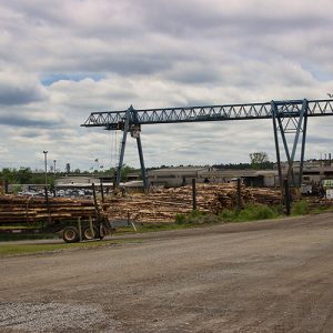 Crane over lumber yard with warehouse buildings and dirt roads