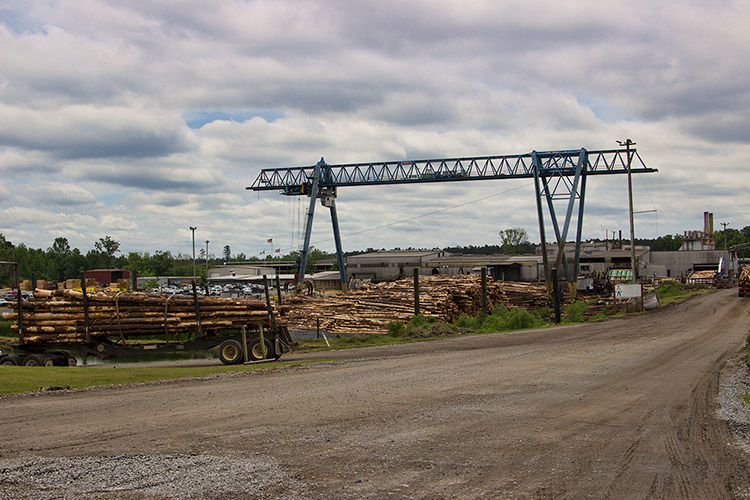 Crane over lumber yard with warehouse buildings and dirt roads