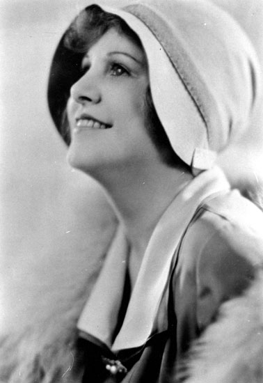 White woman in hat and fur coat with face tilted up and smiling