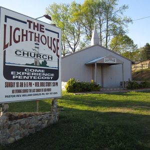 Single-story church building with steeple and sign saying "come experience pentecost"