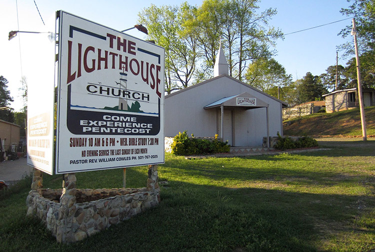 Single-story church building with steeple and sign saying "come experience pentecost"