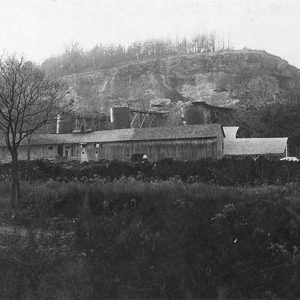 Single-story storefront and lime kiln building alongside hill with trees in the foreground