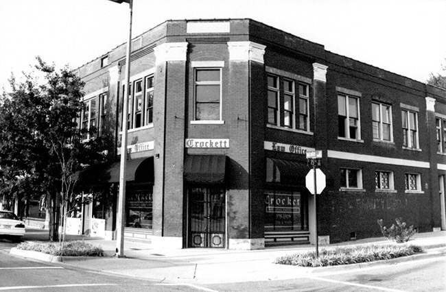 Brick building on street corner with "Crockett Law Office" signs and logo on windows