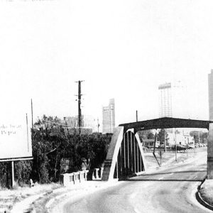 Concrete arch bridge on city street with tall buildings in the background