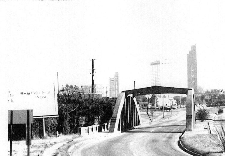 Concrete arch bridge on city street with tall buildings in the background