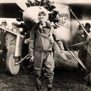 Young white man in pilot's uniform standing with airplane