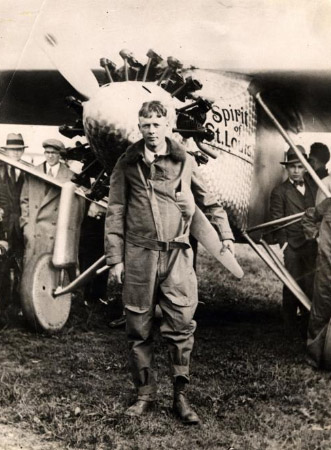 Young white man in pilot's uniform standing with airplane