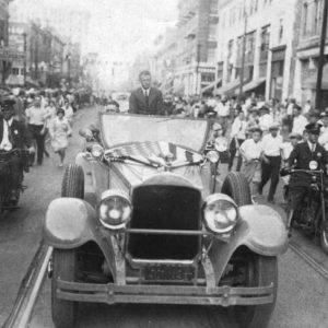 Parade featuring white man riding in convertible