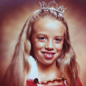 Young white girl smiling in red dress and tiara