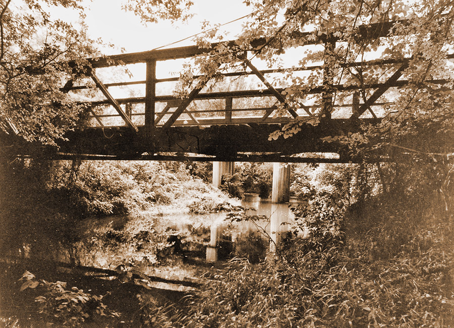 Side view of steel truss bridge with water underneath