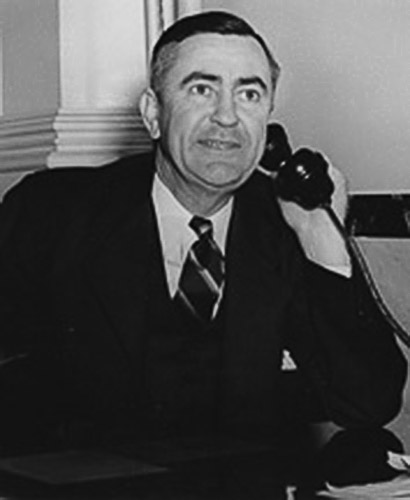 White man in suit and tie using a telephone